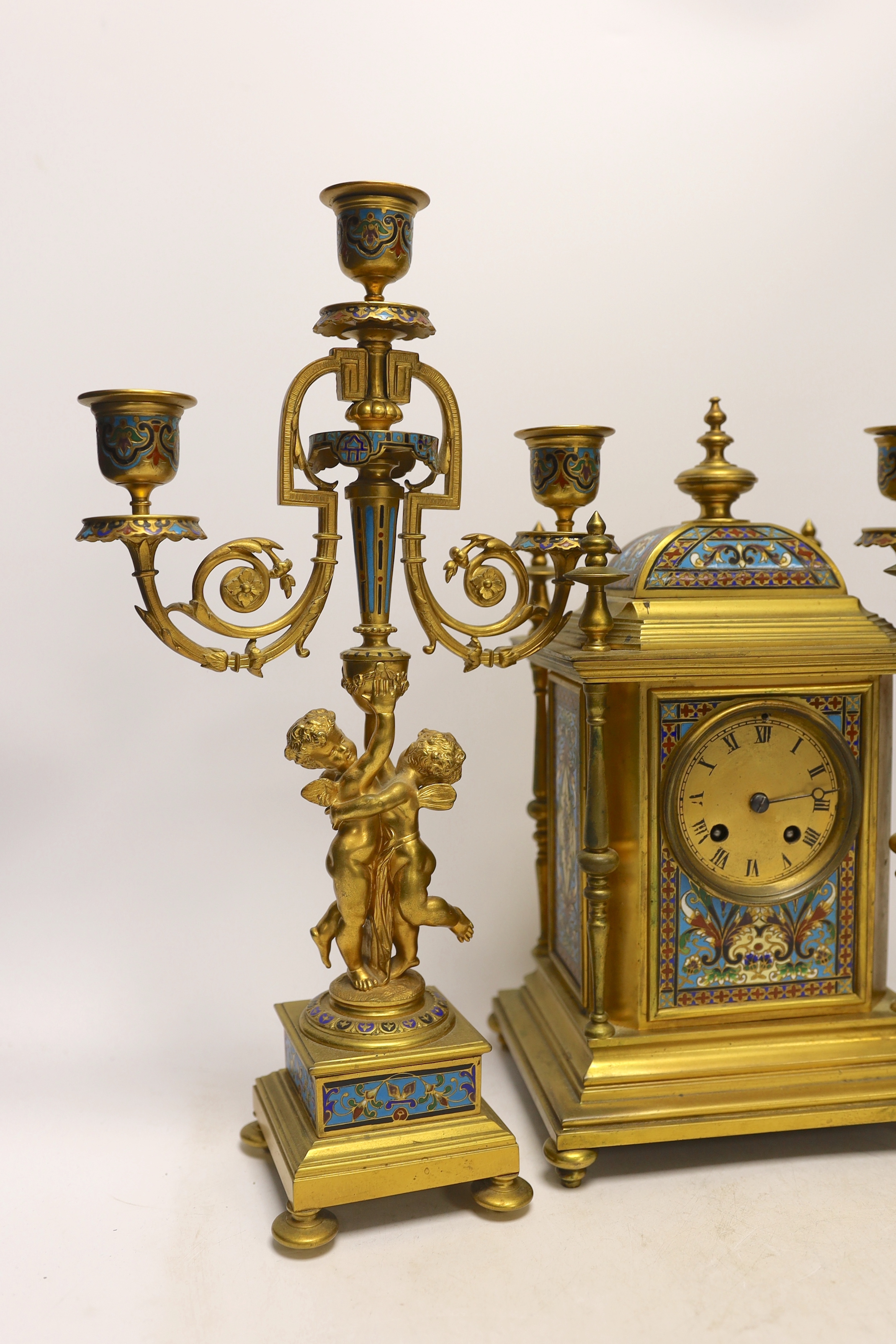 A late 19th/early 20th century French champleve and gilt metal clock garniture, 37cm